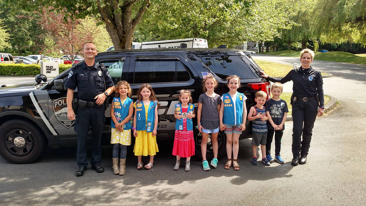 The newest Mercer Island police officer, Alex Rutter (left), provided a tour for a Mercer Island Girl Scout Troop and two little brothers on June 8. At the conclusion of the tour, the kids were good sports and agreed to pose for a picture with Rutter and MIPD Services Commander Leslie Burns. Photo courtesy of MIPD