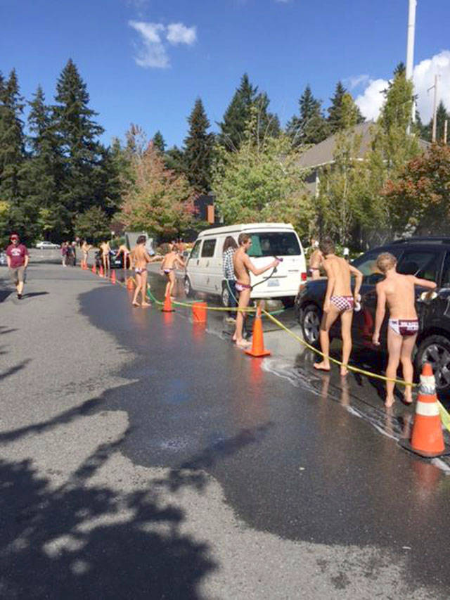 Members of the Mercer Island High School boys water polo team wash cars during the team’s annual fundraiser last year. Courtesy photo