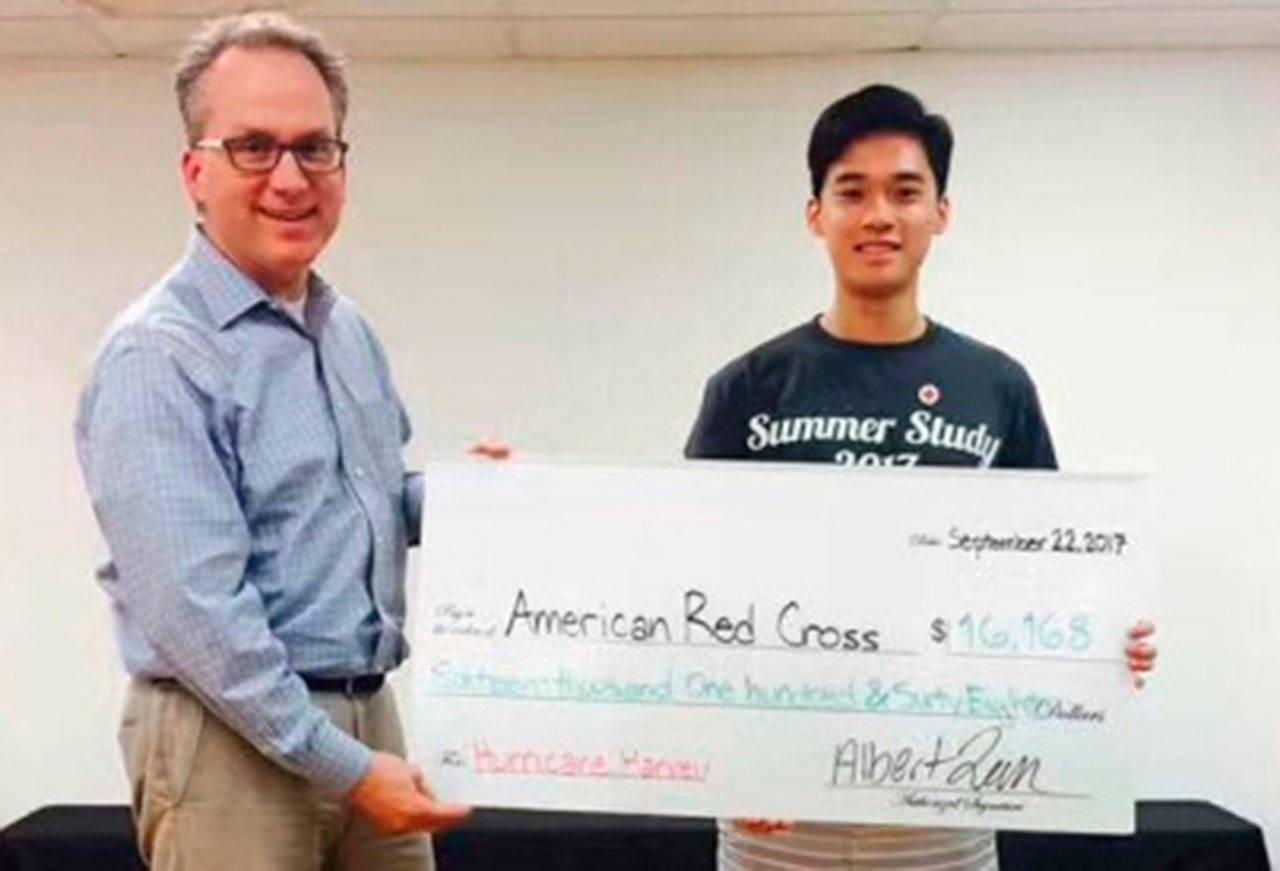 Steven Greimann accepts a check from Albert Lam on behalf of the American Red Cross. Photo via redcrossnw.org