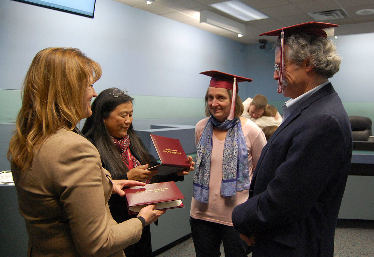 Superintendent Donna Colosky and Mercer Island High School Principal Vicki Puckett give retiring school board members Adair Dingle and Dave Myerson caps and honorary diplomas on Dec. 14. Katie Metzger/staff photo