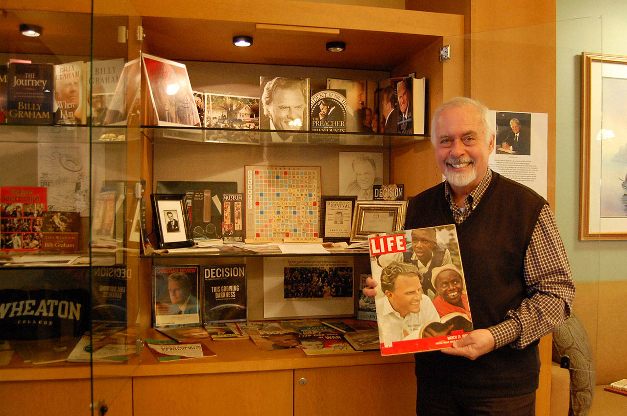 Rev. Greg Asimakoupoulos holds up a vintage Life magazine with Billy Graham on the cover. Asimakoupoulos’ memorabilia collection of the late famous preacher is on display at Covenant Shores Retirement Community. Katie Metzger/staff photo