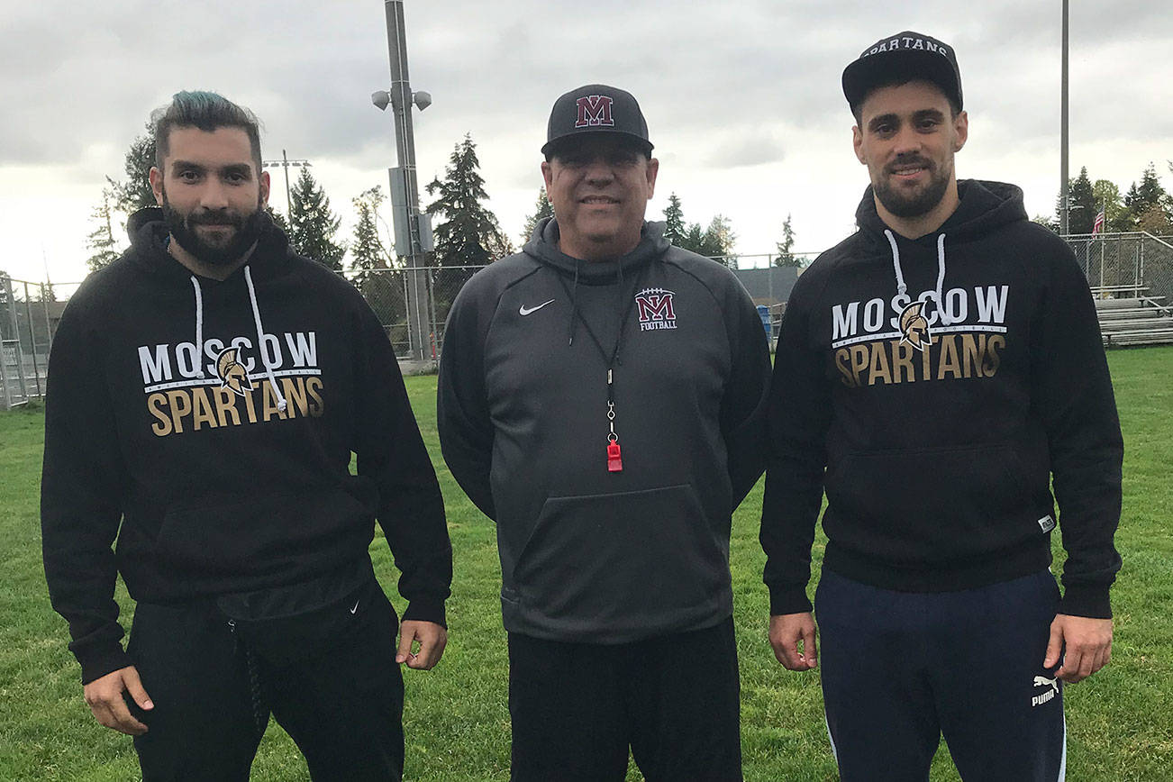 Moscow Spartans football players Omari Grinyaev, Michael Levenshtein and Mercer Island head football coach Ed Slezinger pose for a quick photo prior to the start of Mercer Island’s football practice on Oct. 9. Grinyaev and Levenshtein will be in Washington observing the Islanders football programs practices, meetings, workouts and games through Oct. 22. Shaun Scott/staff photo