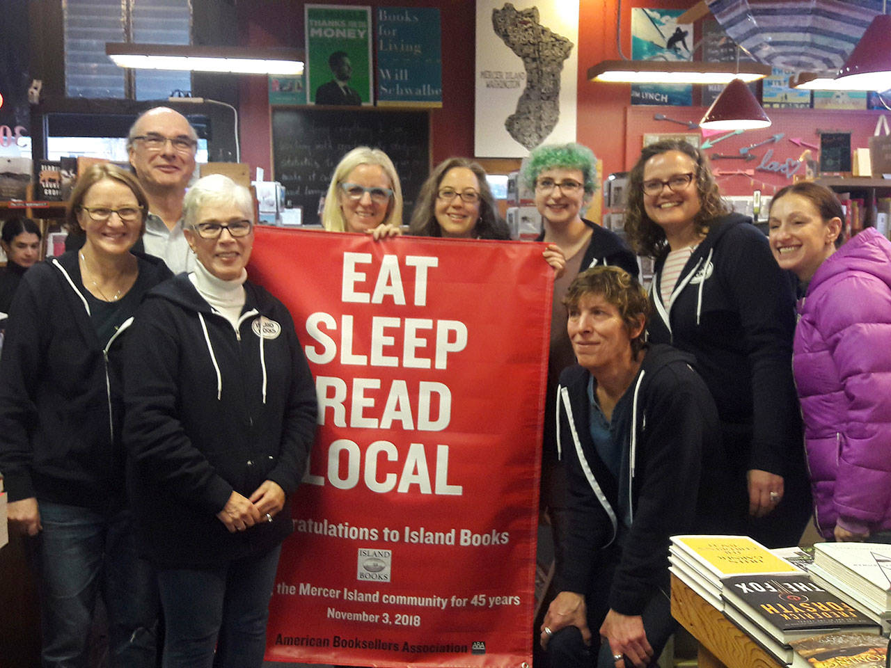 The Island Books staff, including owner Laurie Raisys, smile with a banner honoring their 45 years on Mercer Island. Photo courtesy of Nancy Shawn
