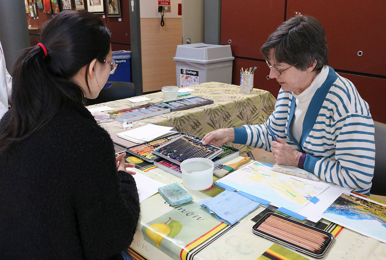 Judy Mortiz of Northwest Artists in Action teaches Mercer Island resident Kelly Shi about creating art with colored pencils during a pop-up demonstration on Jan. 26. Katie Metzger/staff photo