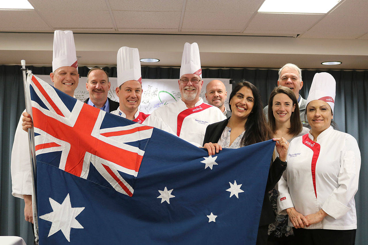 Chef Steve Laybourn, Covenant Shores Dining Director Neetu Saini, Executive Director Bob Howell, Chef Laura Gabriel and more pose with an Australian flag after a cooking demonstration on March 1, when residents of the Mercer Island retirement community got to try kangaroo and alligator. Katie Metzger/staff photo
