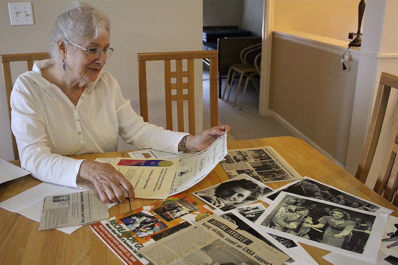 Linda Tammone, daughter of “Wizard of Oz” extra Meredythe Glass, looks through her mother’s photographs, newspaper clippings, cards and memorabilia in Glass’s former apartment at Covenant Shores on Sept. 5. Madison Miller / staff photo
