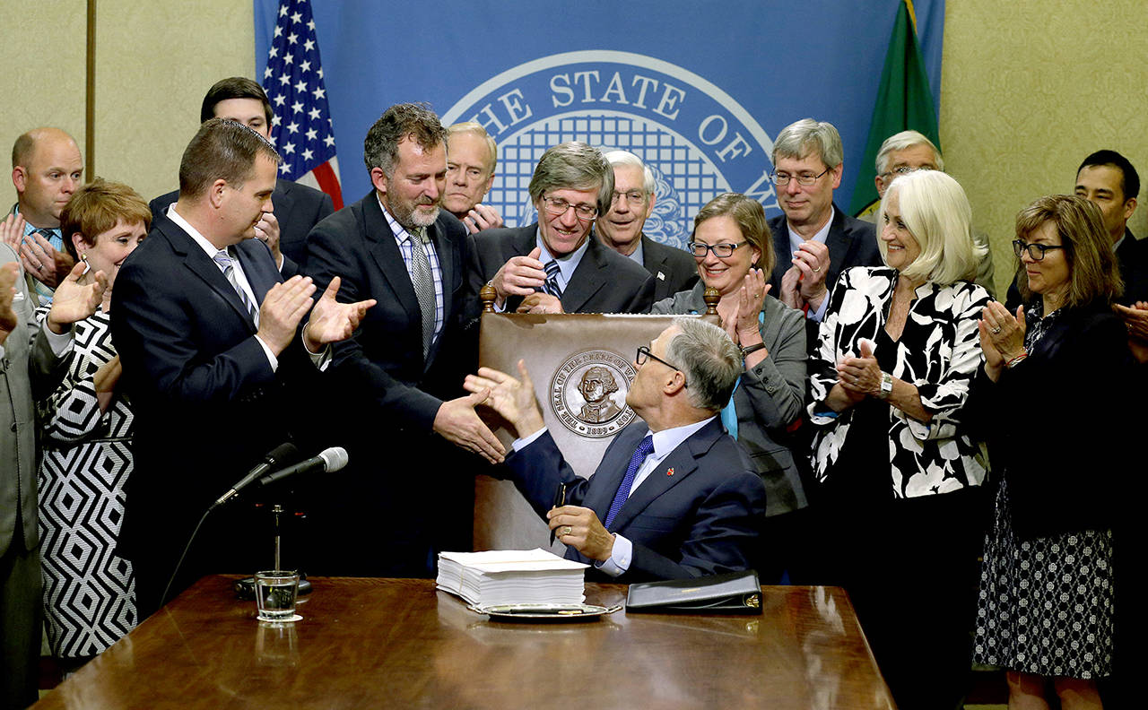 Washington Gov. Jay Inslee (center) shakes hands after he signed a two-year state operating budget on June 30, 2017, at the Capitol in Olympia. (AP Photo/Ted S. Warren, file)