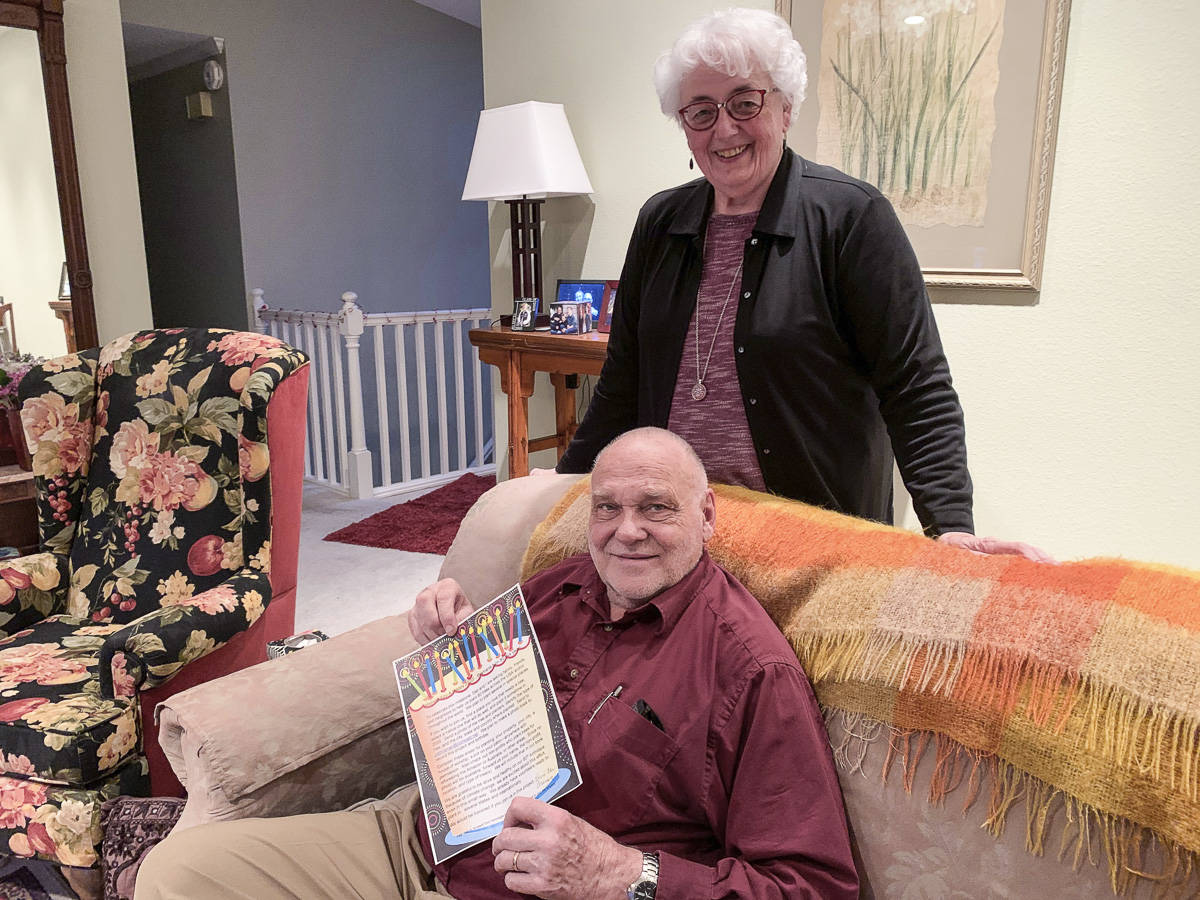 In their Mercer Island home, Pat and Dan Braman pose with a flier asking friends and family to plant 80 trees for their 80th birthdays and to help the environment. Natalie DeFord/staff photo