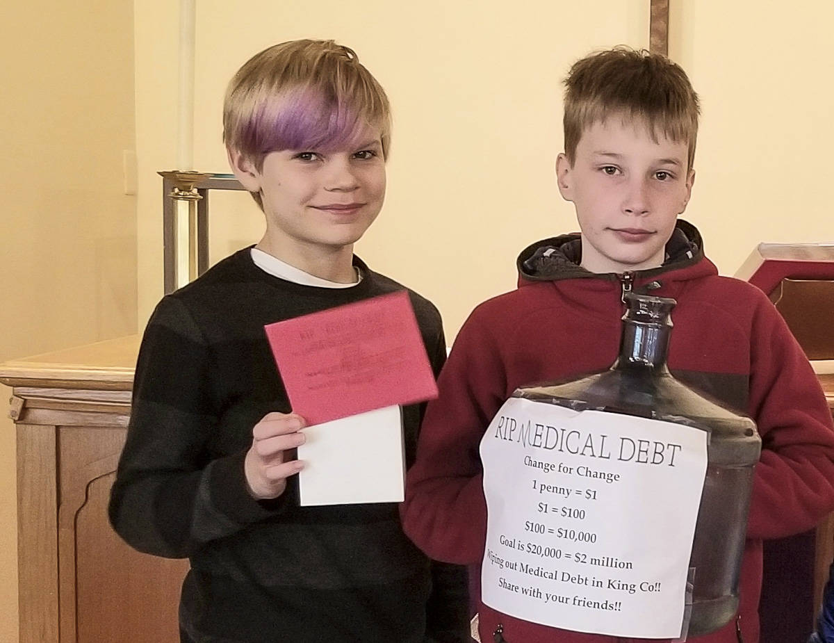 Courtesy photo                                Brody Newcomer (left) and Matthew Duffie, two Sunday school children at Holy Trinity Lutheran Church on Mercer Island, pose with a change collection bank for the church’s Lent fundraiser with RIP Medical Debt.