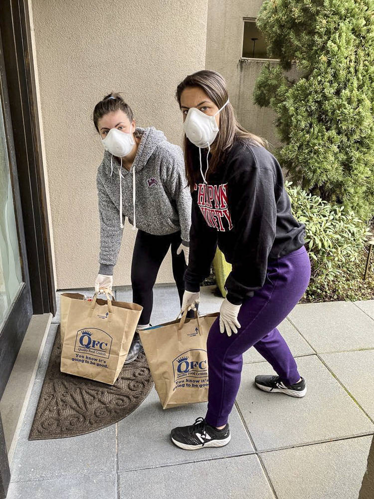 Sisters Mackenzie Wilson (left) and Natalie Wilson delivering groceries to a neighbor’s doorstep. Courtesy photo