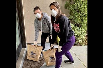 Sisters Mackenzie Wilson (left) and Natalie Wilson delivering groceries to a neighbor’s doorstep. Courtesy photo