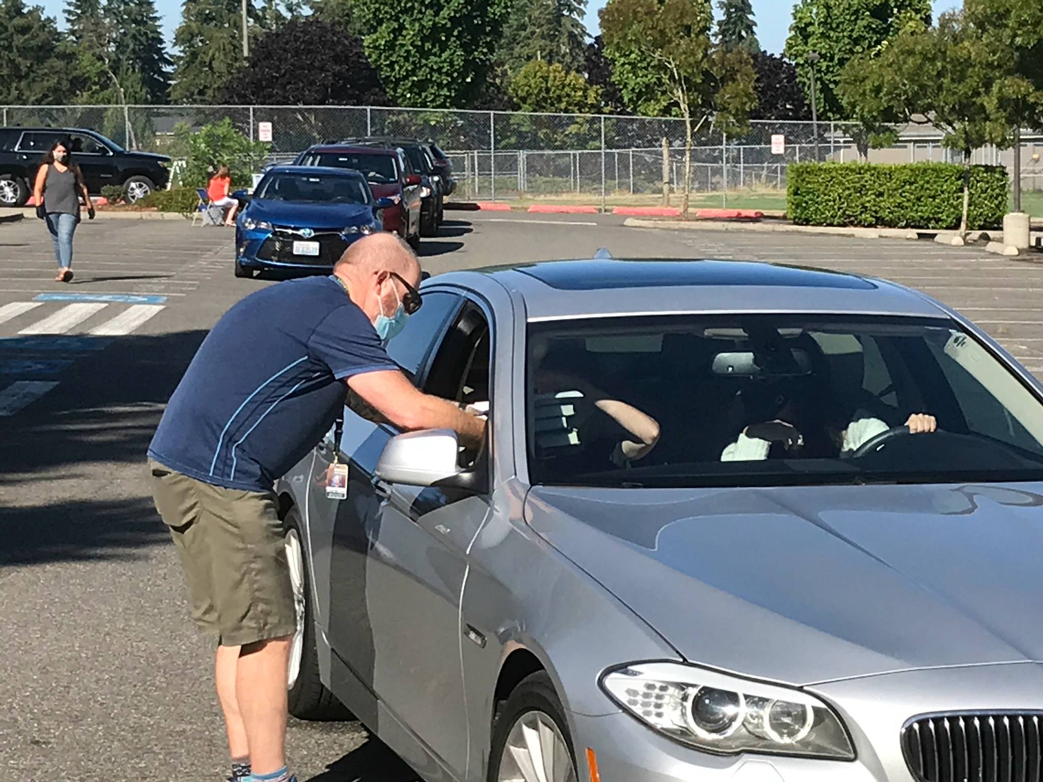 Mercer Island High English teacher Gregg Smiley distributes textbooks to a freshman on Aug. 25 during the first day of back to school drive-up services for students/parents to pick up their books, turn in any overdue books and pick up an iPad for new students. Sophomores also arrived at school for drive-up services on Aug. 25, and juniors and seniors came back for those same services on Aug. 26. School district remote classes will begin on Sept. 2. Photo courtesy of the Mercer Island School District