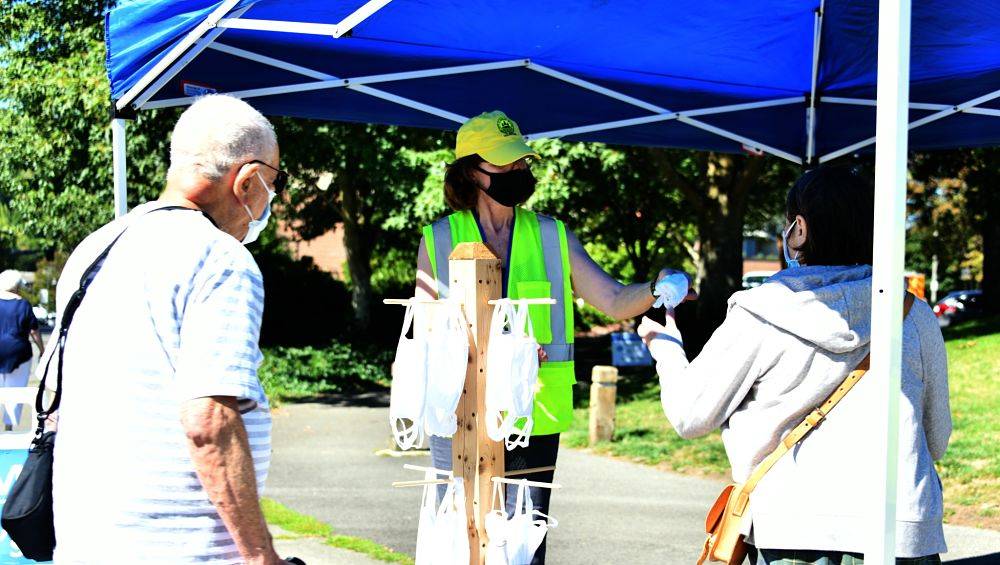 Pat Hackett hands out free masks to people on Aug. 28 at the former Tully’s lot in Mercer Island Town Center. Photo by Andy Nystrom/ Reporter