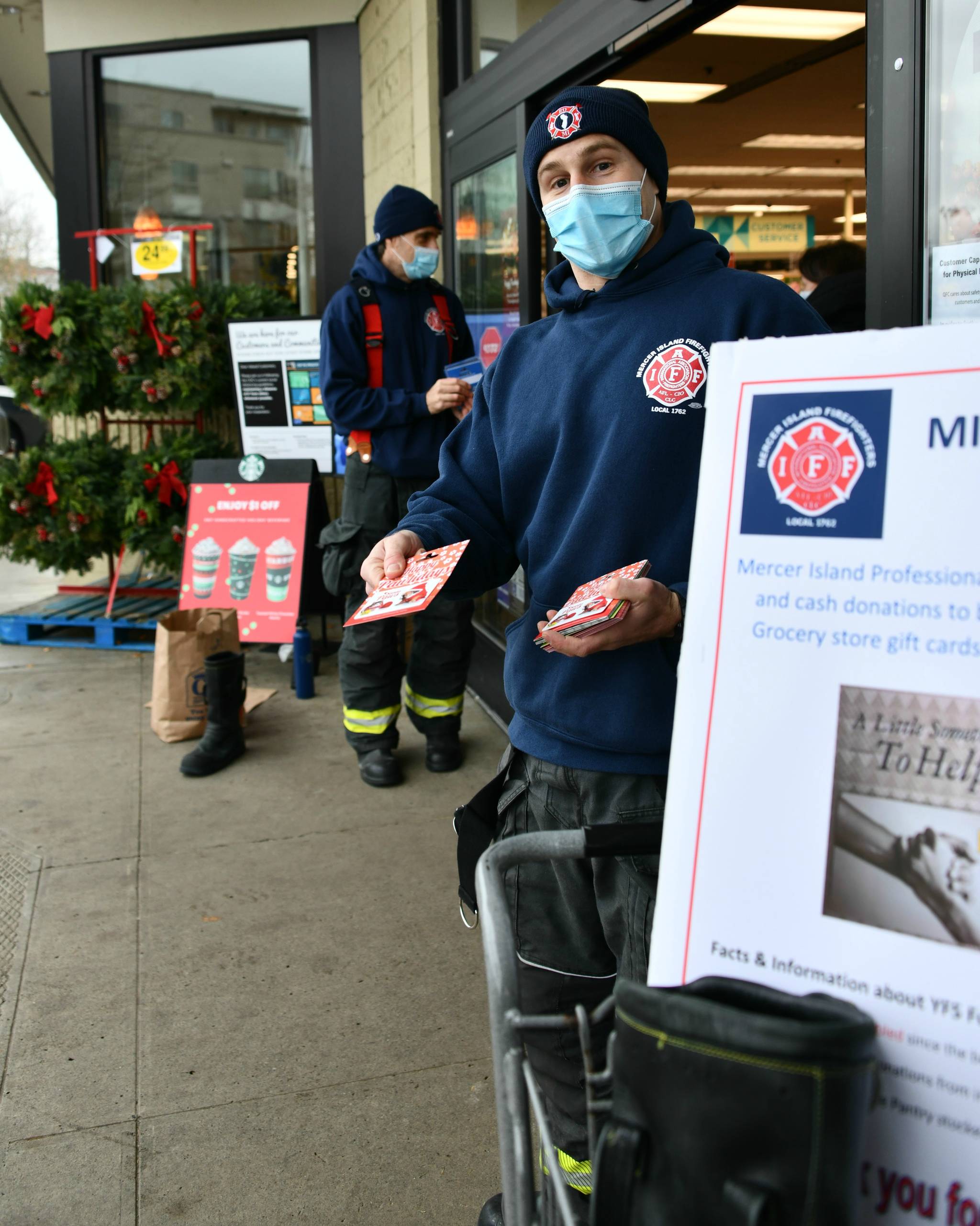 Mercer Island firefighter Jeff Collins (front) and battalion chief Stephen Mair collect donations for QFC gift cards that will be given to the city’s Youth and Family Services Food Pantry. They are pictured at QFC north on Nov. 25, and firefighters also collected donations at QFC south on that same day. Andy Nystrom/ staff photo