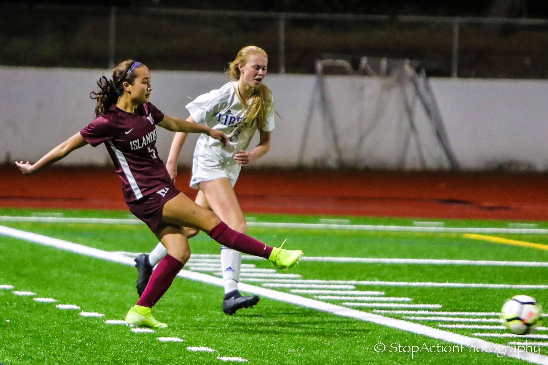 In this 2019 photo, Mercer Island’s Emily Yang, left, takes a shot on goal against Liberty. Photo courtesy of Don Borin/ StopActionPhotography
