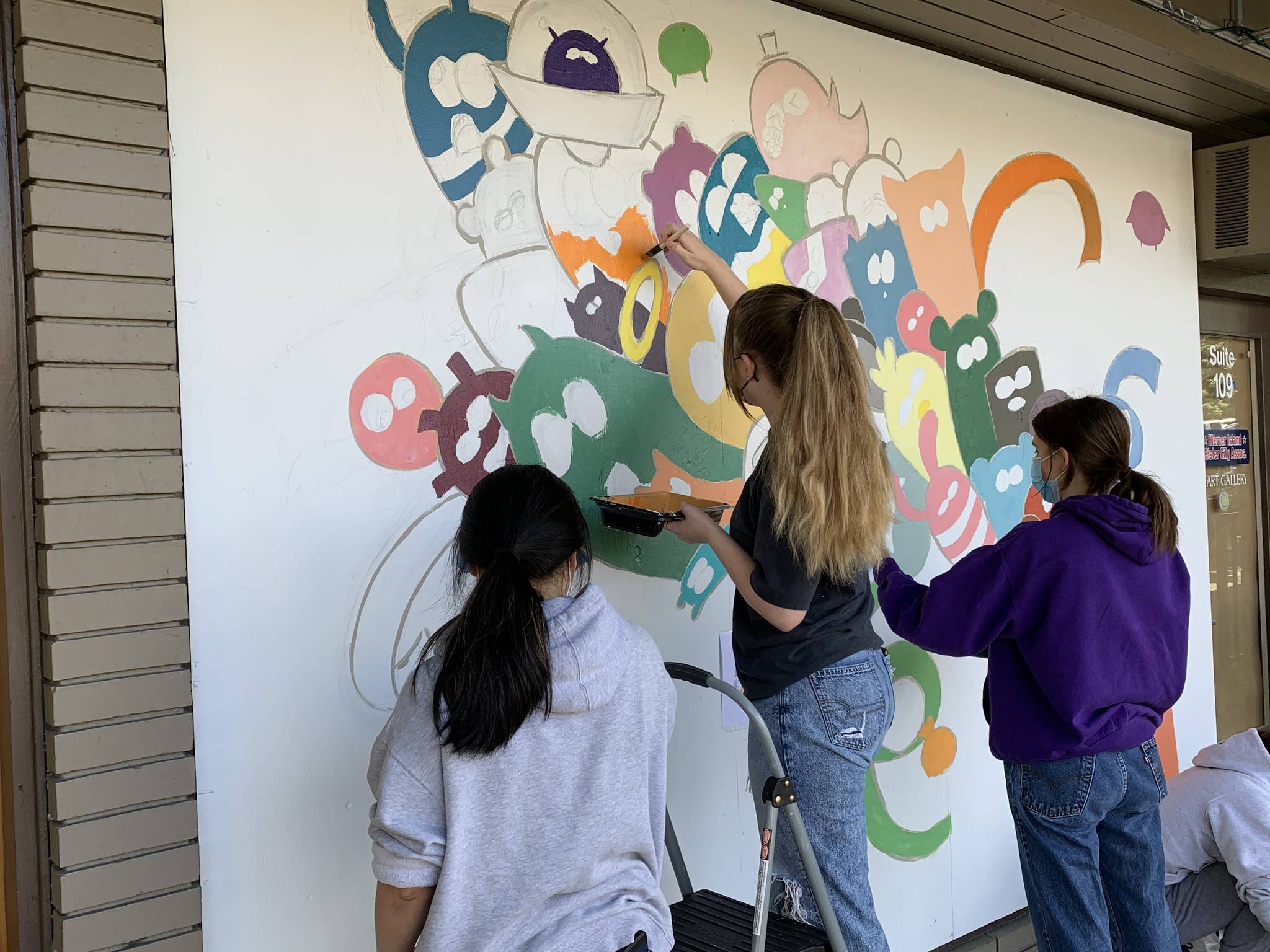 Members of the Mercer Island High School Art Club paint a mural on a recent day, in conjunction with the Mercer Island Visual Arts League (MIVAL), at the Mercer Island Chamber of Commerce building. Photo courtesy of Greg Asimakoupoulos