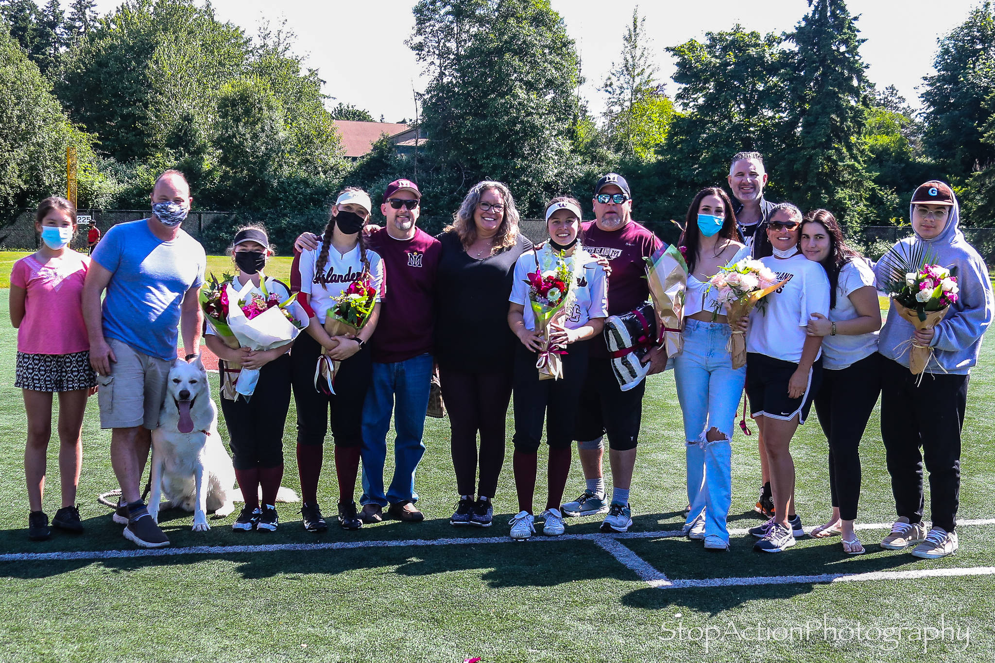 Senior Mercer Island High School fastpitch players, from left to right, Lauren Majewski #21, Chloe Larson #8, Michelle Lyon #16 and Charlise Barokas #7 (not in uniform) gather with their families on senior night on June 4. Photo courtesy of Don Borin/ StopActionPhotography