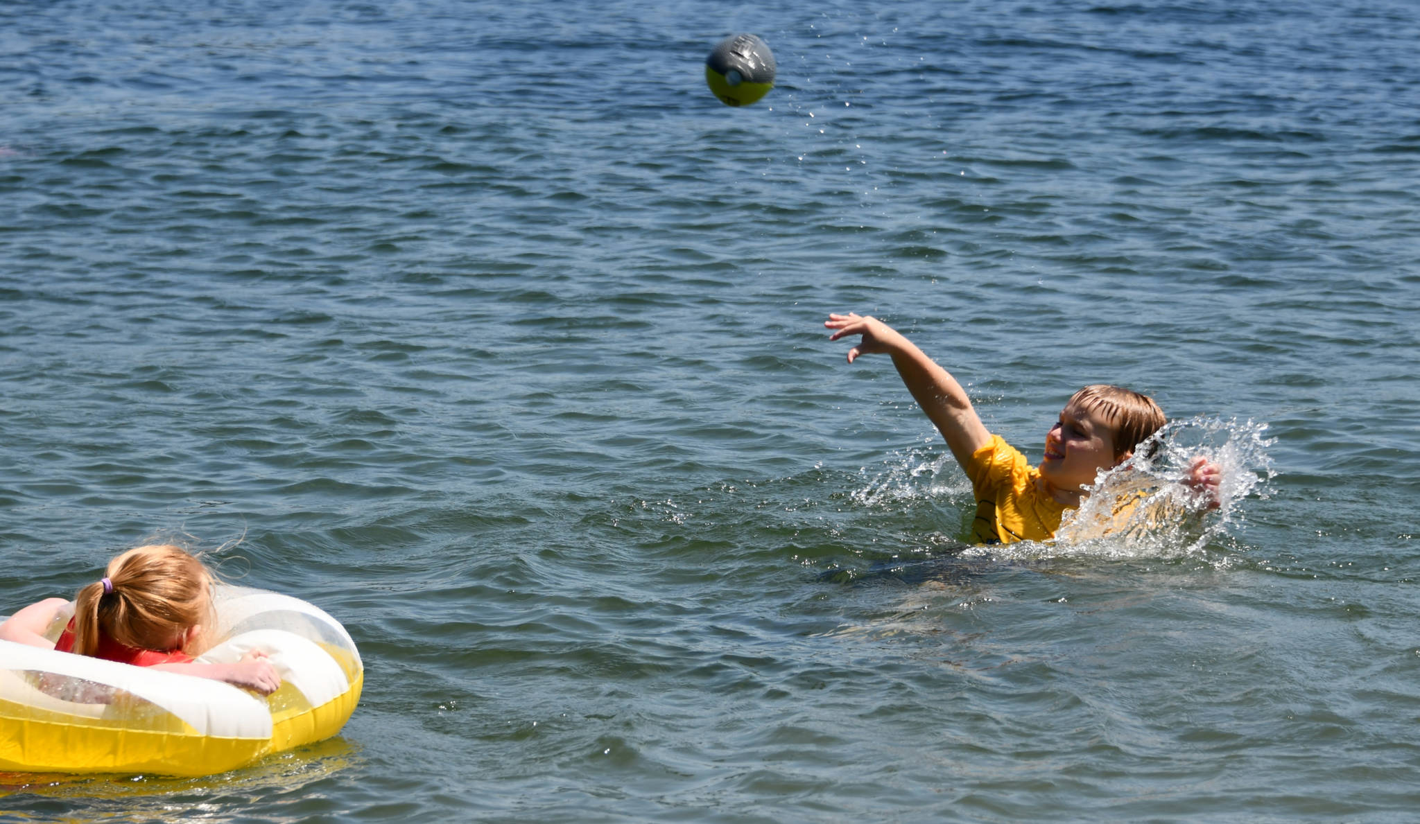 Rowan Ward tosses a football in Lake Washington off Luther Burbank Park on a sunny June 29. His sister Sienna watches. They were playing with their grandparents, Barb and Scott Middleton. Temperatures hit the mid- to upper-80s on this day, a far cry from the 100s on the previous days. Andy Nystrom/ staff photo