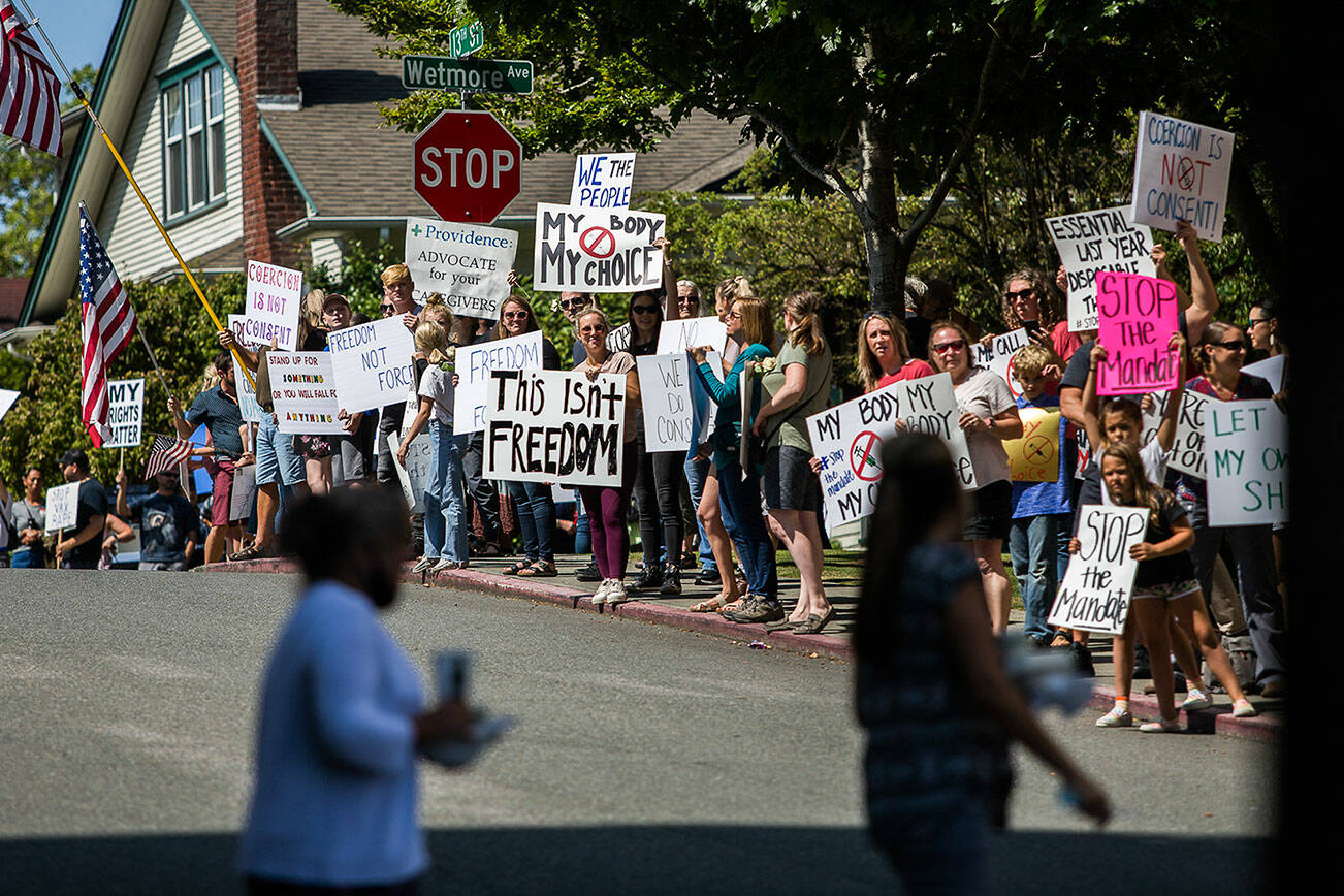 Providence employees look at anti-vaccine mandate protesters as they cross the street outside of Providence Regional Medical Center Everett on Aug. 18, 2021. Olivia Vanni/Sound Publishing