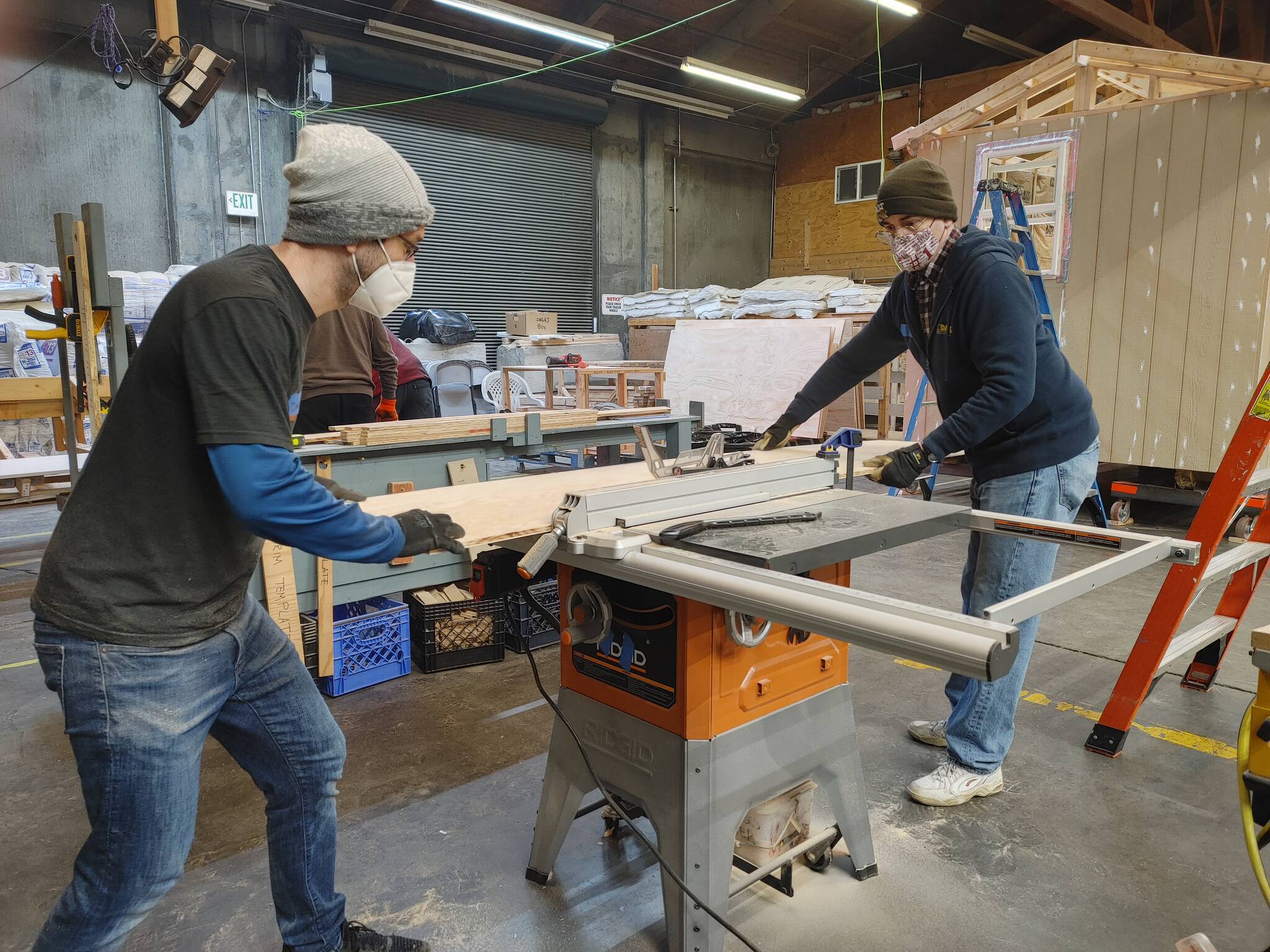 Mercer Islanders Daniel Becker, left, and Ted Weinberg get in some sawing action while building part of a tiny house on Jan. 15 at the Low Income Housing Institute factory in south Seattle. Andy Nystrom/ staff photo