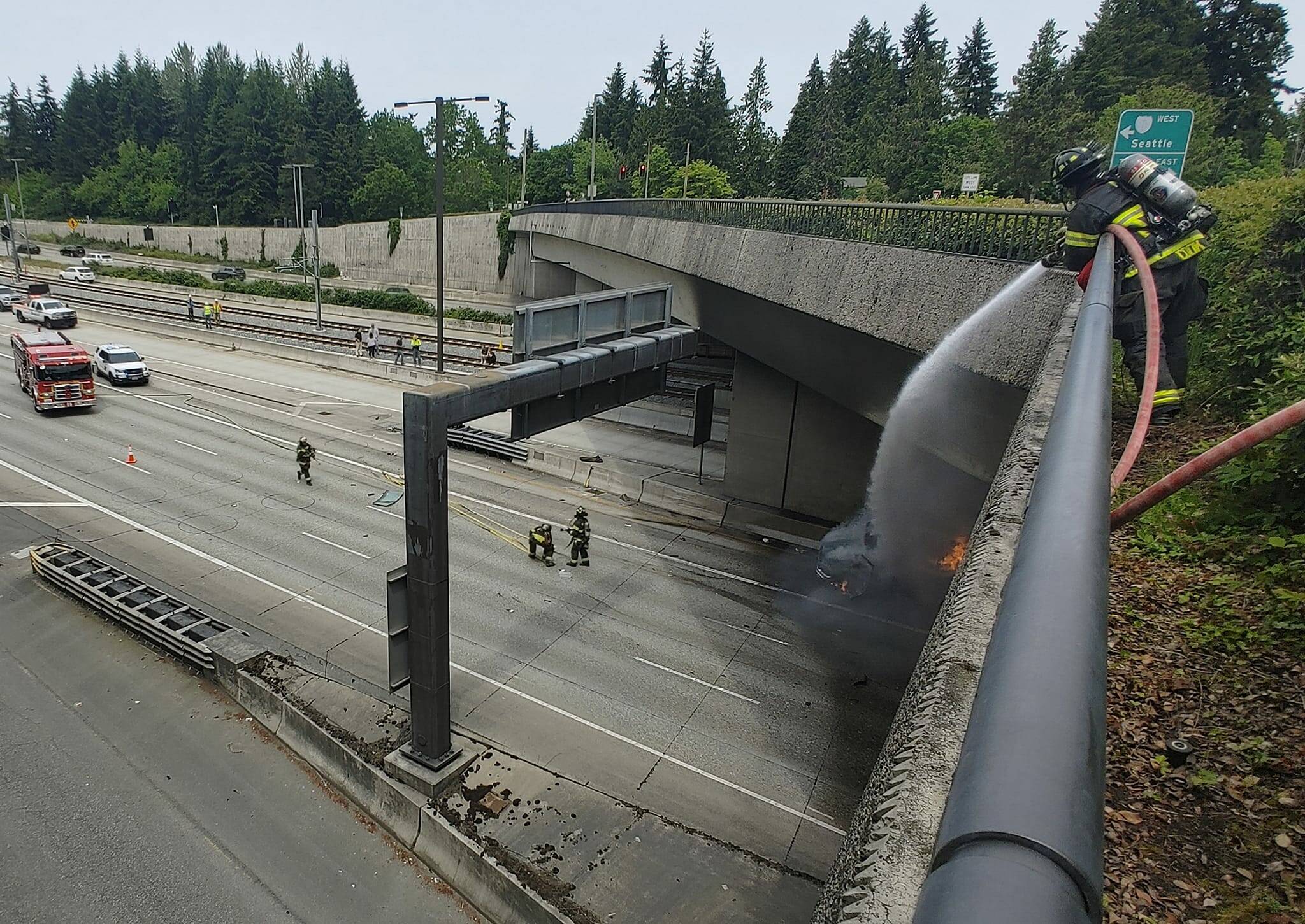 A Mercer Island firefighter douses a burning van on Interstate 90 east below 72nd Avenue Southeast on the afternoon of June 1. Andy Nystrom/ staff photo