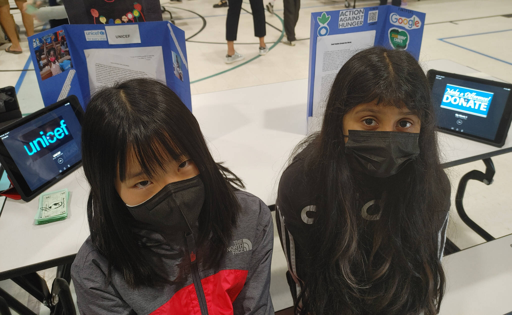 Left to right, Lakeridge Elementary School fifth-graders Lucy Hao and Anya Patel researched UNICEF (United Nations International Children’s Emergency Fund) and Action Against Hunger, respectively, for the “Merchants with a Cause” program. Andy Nystrom/ staff photo