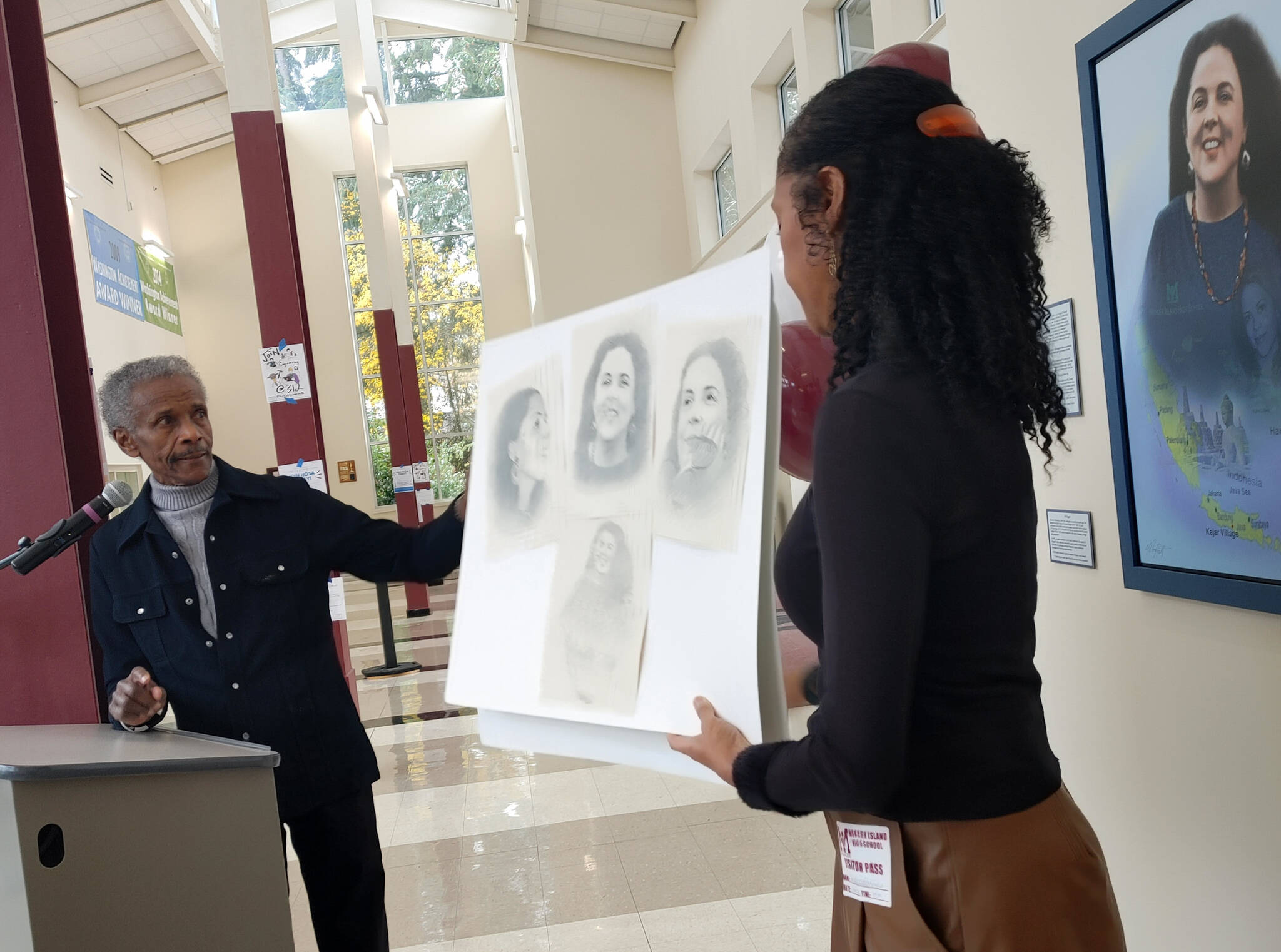 Artist Al Doggett is joined by Michelle Flowers-Taylor, board chair of the Stanley Ann Dunham Scholarship Fund, on Nov. 29 in describing his technique in drawing a portrait of Dr. Dunham that hangs (at right) in the foyer at Mercer Island High School. Andy Nystrom/ staff photo