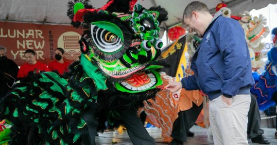 Edmonds Mayor Mike Nelson rewards a lion dancer with a traditional red envelope during a celebration of the Lunar New Year on Saturday, Jan. 21, 2023. Photo by Ryan Berry / The Herald