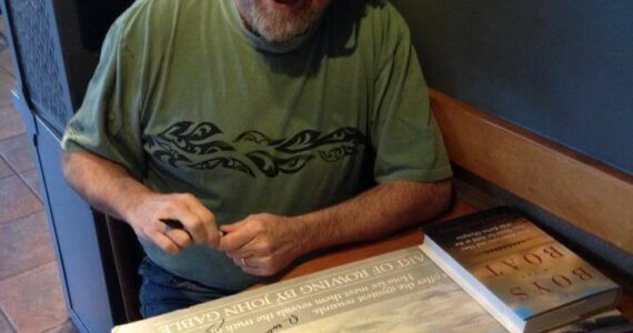 In this 2013 photo, Daniel Brown (author of “The Boys in the Boat”) signs a poster for Greg’s brother Marc, who was a coxswain for the SPU crew team in the 1970s. (Photo courtesy of Greg Asimakoupoulos)