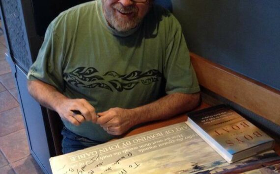 In this 2013 photo, Daniel Brown (author of “The Boys in the Boat”) signs a poster for Greg’s brother Marc, who was a coxswain for the SPU crew team in the 1970s. (Photo courtesy of Greg Asimakoupoulos)
