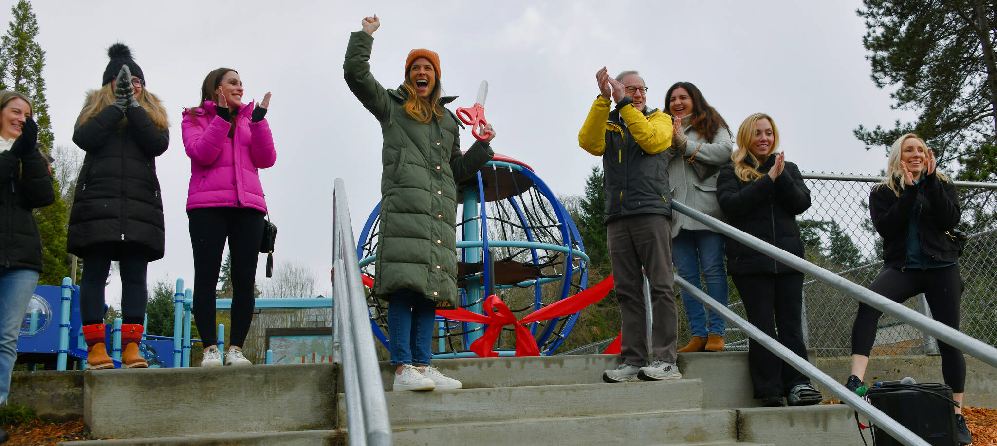 West Mercer Elementary School PTA President Sarah Hollenbeck (middle) enthusiastically leads the ribbon-cutting ceremony to celebrate the grand opening of the school’s new playground on Jan. 11. She is joined by PTA board members Jen Lyons, Rachel Lumpkin, Robin Pearson, Lisa Kalscheur, Lauren Milkie and Adrienne Peterson, along with substitute Principal David Hoffman. Andy Nystrom/ staff photo