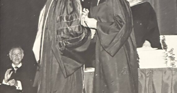 President David McKenna kisses his wife after presenting her her college diploma (June 1974) Greg’s father applauds in the lower left hand corner. Courtesy photo