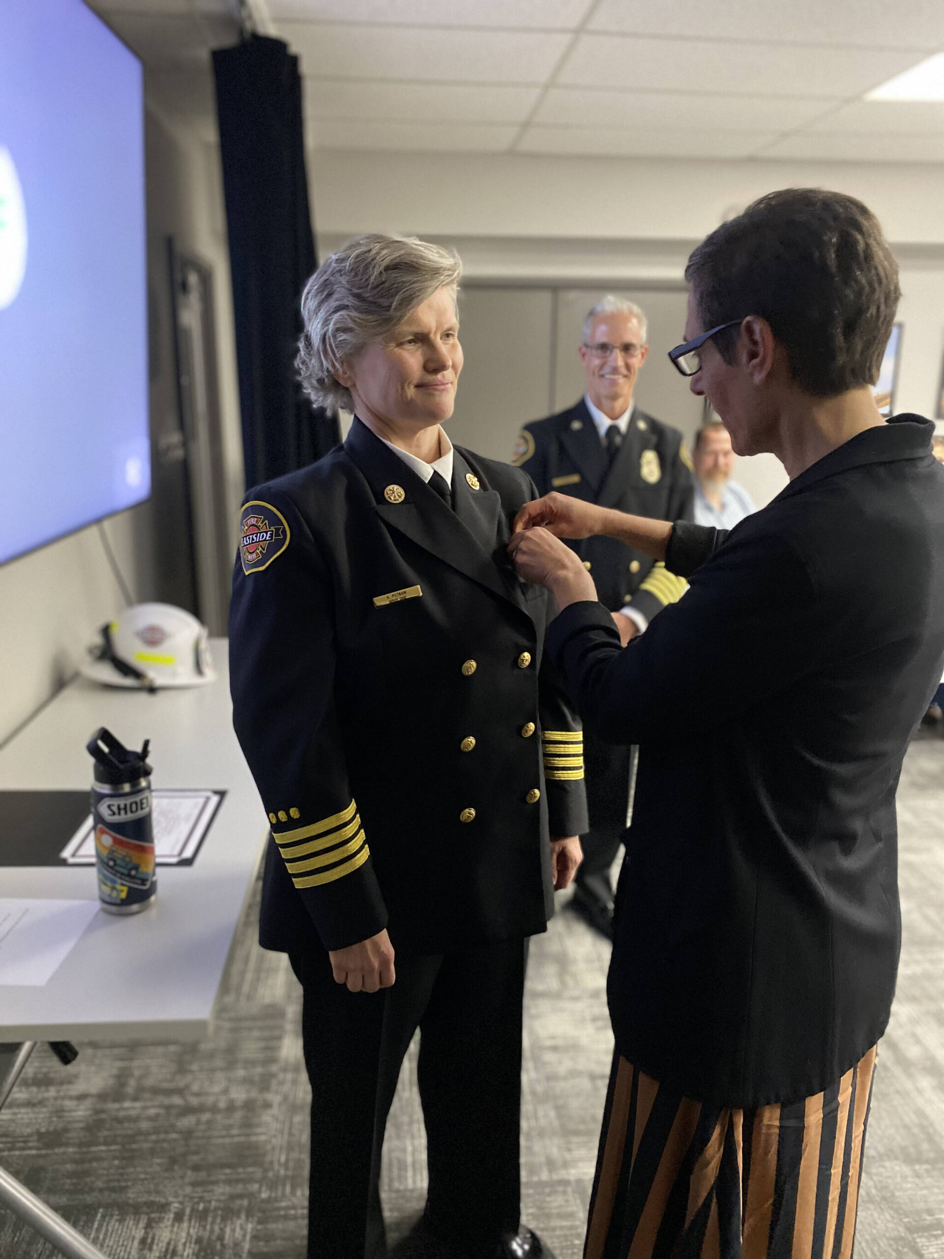 Eastside Fire & Rescue’s (EF&R) Kara Putnam, left, is Mercer Island’s new deputy fire chief. Here, she is sworn in at a recent EF&R ceremony alongside her wife Margot Rosenberg. Former fire chief Ben Lane is in the background. Photo courtesy of Eastside Fire & Rescue