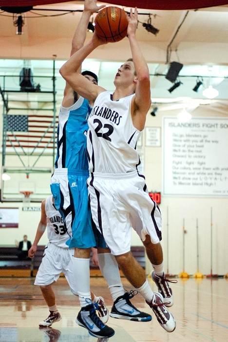 Islander forward Quinn Sterling (22) drives to the basket against a Saints defender at Mercer Island on Friday.