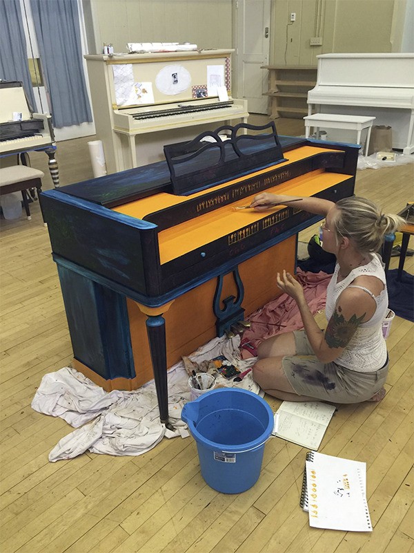 An artist works to design and decorate an instrument for Pianos in the Parks. All 22 previously owned pianos are procured