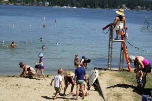 A lifeguard watches children swim during a hot afternoon at the Luther Burbank Park swim beach on Tuesday