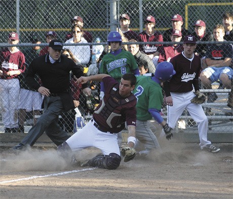 Mercer Island catcher Ben Emanuels tries to get to the ball as a Liberty player crosses home plate to score in the top of the seventh inning. The Islanders won the game 7-6 in extra innings for a piece of the KingCo title