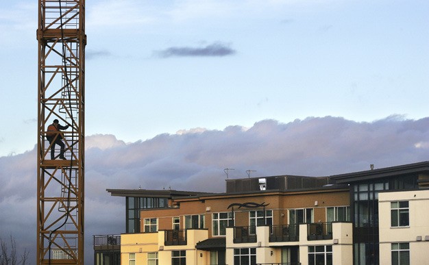 A worker climbs the crane at the Aviara mixed-use development along 76th Avenue S.E. facing the senior living building