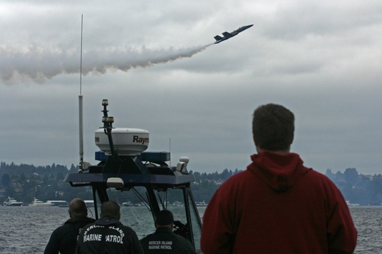 Two Mercer Island Marine Patrol Officers and a State Patrol Officer watch the Blue Angels show Friday from their Marine Patrol Unit as another spectator follows the show from a temporary dock that was set up for the weekend at Proctors Landing so law enforcement could use the area as a staging zone for BUI infractions