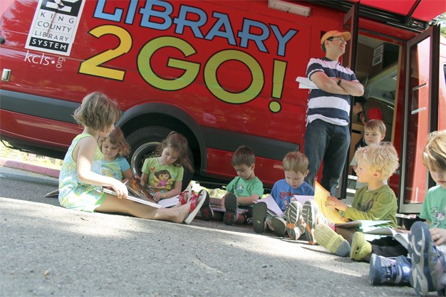 Children from a Stroum Jewish Community Center preschool class read outside of the King County Library System Library2Go van during the annual SJCC truck day event on Thursday