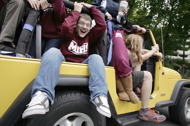Seated on a wheel well in a Jeep with at least 11 seniors aboard