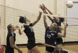 Mercer Island's Lottie MacAulay (10) tips the ball over the net as Lake Washington's Eleanor Lyon (10) and Shelby Farrell (8) try to block it. The Islanders beat Lake Washington 3-1 last Saturday during the district tournament