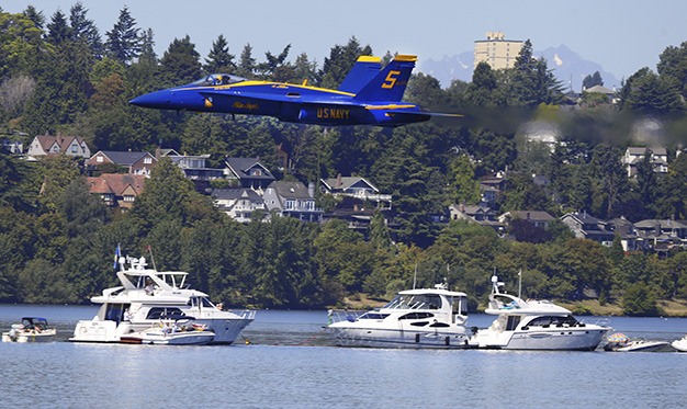 The U.S. Navy Blue Angels make a low pass over hundreds of boats on the log boom on the hydroplane oval on Lake Washington