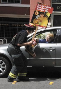 Mercer Island firefighter Curt Groscost accepts a donation from a driver during the annual Fill the Boot fundraising campaign