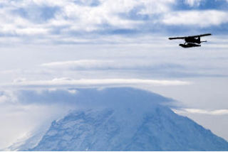 A float plane takes a morning flight against a backdrop of cloud-capped Mount Rainier in this southeastern view from the end of Island Crest Way on Mercer Island.