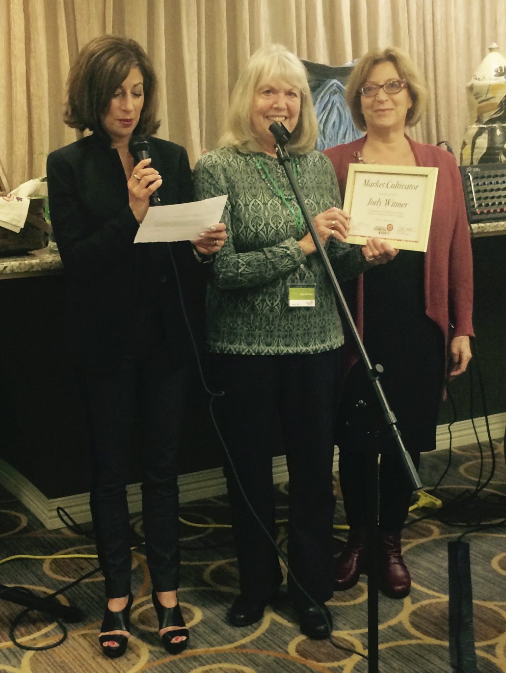 Sharon Perez and Mindy Lindsman present Farmers Market volunteer Judy Witmer with the inaugural "Market Cultivator Award" on May 15 at Aljoya. Photo courtesy of the Mercer Island Farmers Market.