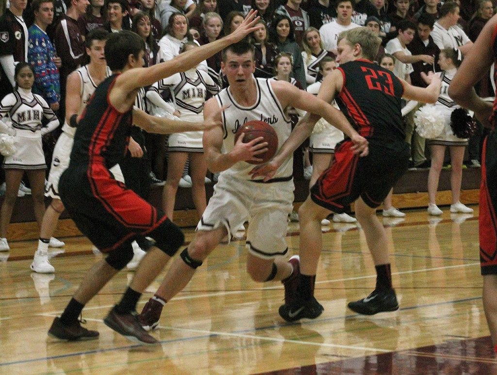 Mercer Island&rsquo;s Griffin Emanuels fights through Sammamish defenders Max Donaldson (left) and Kenneth Rasmussen (23) Friday at Mercer Island High School. The Islanders beat the Totems 66-45. Joe Livarchik/staff photo.