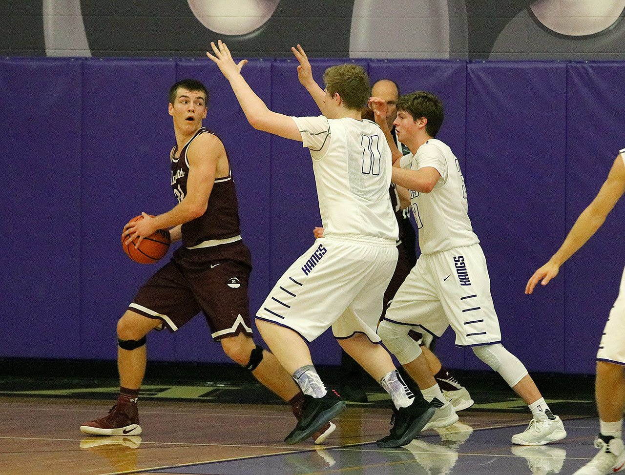 Mercer Island&rsquo;s Griffin Emanuels looks to pass against Lake Washington defenders Griffin Barker (11) and Sam Linsky Friday at Lake Washington High School. The Kangs rallied to beat the Islanders 61-60 (Joe Livarchik/staff photo).