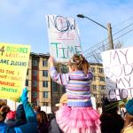 Marchers hold up signs as they walk to Seattle Center. Allison DeAngelis/Bellevue Reporter