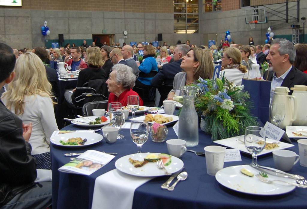 Longtime MIYFS supporter Myra Lupton (in red) listens to keynote speaker Dr. Kevin Haggerty. Haggerty was one of Lupton&rsquo;s students when she taught American literature at Sammamish High School. Katie Metzger/staff photo